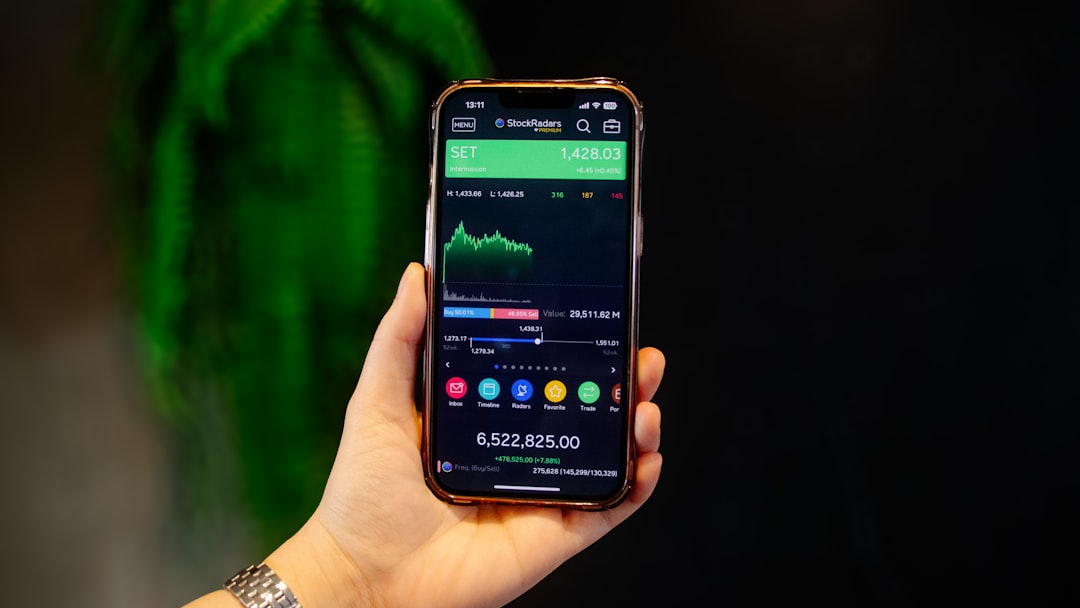Hand Holding Smartphone with Stock Market Analysis Chart Dashboard Portfolio on Screen